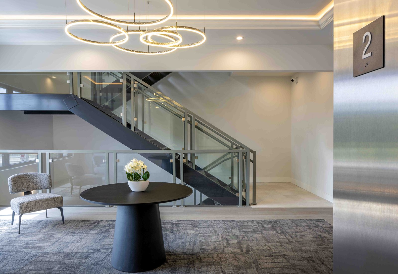 Ocean Breeze Lofts interior — floating staircase, ring chandelier, and second-floor landing